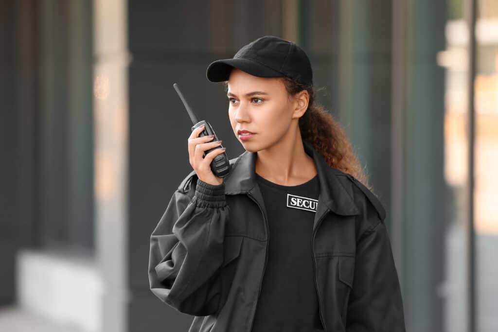 African-American female security guard with radio transmitter near building outdoors